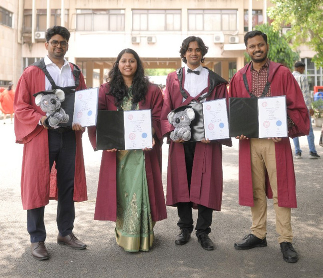 4 UQ-IITD students in IITD India with their degrees and Koala soft toy