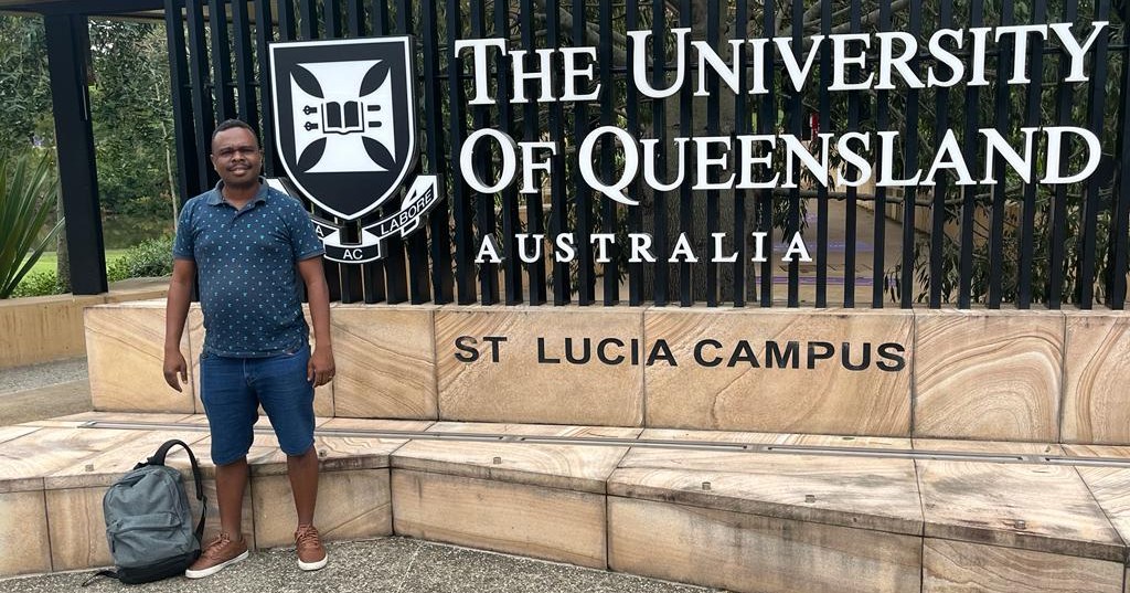 Nelson in front of UQ signage at UQ St Lucia