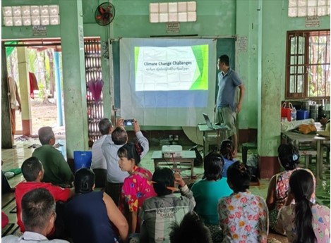 Climate Change Challenge - in small building farmers looking at power point on cloth screen