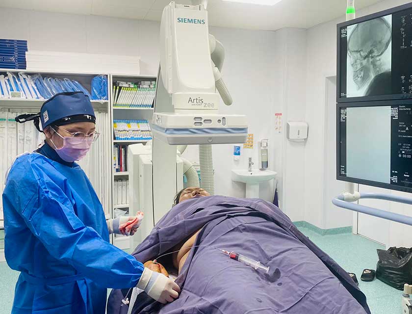 Dr  Ambaselmaa Bayarsaikhan wearing blue scrubs and a mask, operating on a man at the Central Regional Diagnostic and Treatment Center in Ovorkhangai Province, Mongolia. 