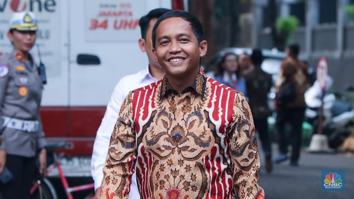 A smiling man (Raja Juli Antoni) wearing a brightly coloured shirt walks in the street in Indonesia.