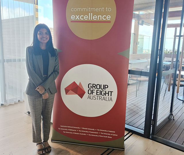 Satorupa Karmaker standing with a banner at the Go8 meeting in Sydney.