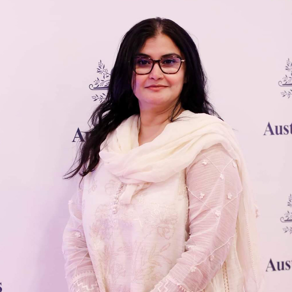 Saima Mazhar with an Australia Awards banner behind her.