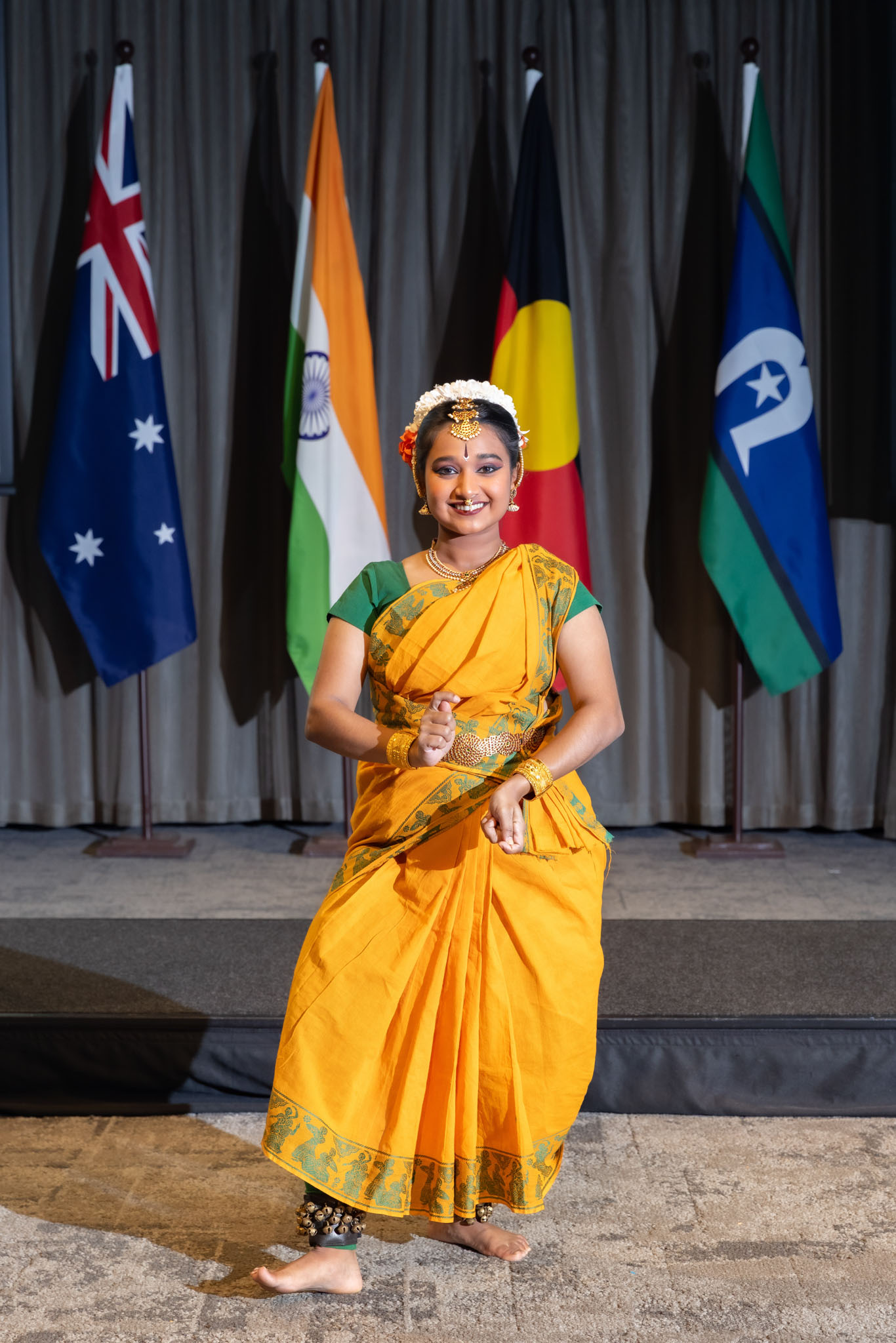 Likitha Rajashekhar in full Indian traditional dress performing in front of flags of Australia, India, Aboriginal and Torres Strait Islanders