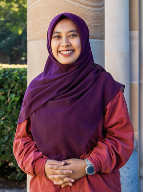 Ifa wearing a hijab at UQ St Lucia with sandstone pillars of the Great Court behind her