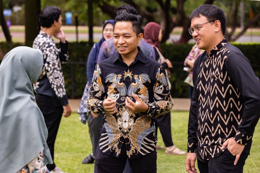 Two men and one woman wearing traditional clothing talking on UQ St Lucia grounds