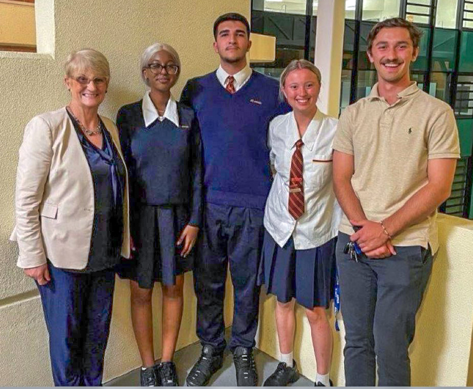 Taha standing with students of debating team with female Principal on the left and male debating coach on the right
