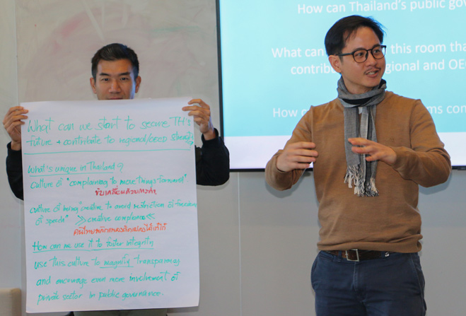 Prachya standing up and speaking off notes during a workshop