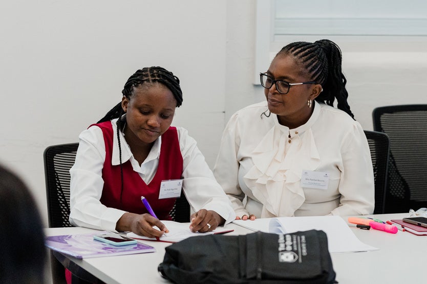 Ruth sitting next to her mentor Mrs Rachiel Bvurire looking over Ruth's work