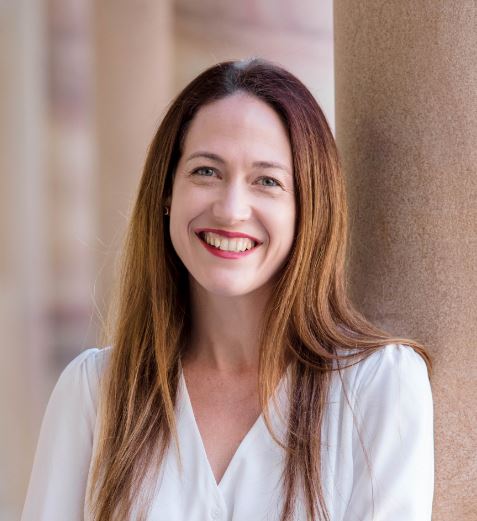 Dr Jessica Gallagher wearing a silk shirt and standing in the Great Court at St Lucia UQ