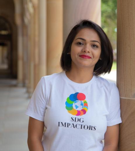 Runali wearing her t-shirt with circles shaped like a shell with the 17 colours representing the sustainable development goals of the United Naitons. 