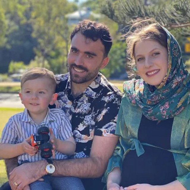 Omid and his wife and son seated on a bench with the 