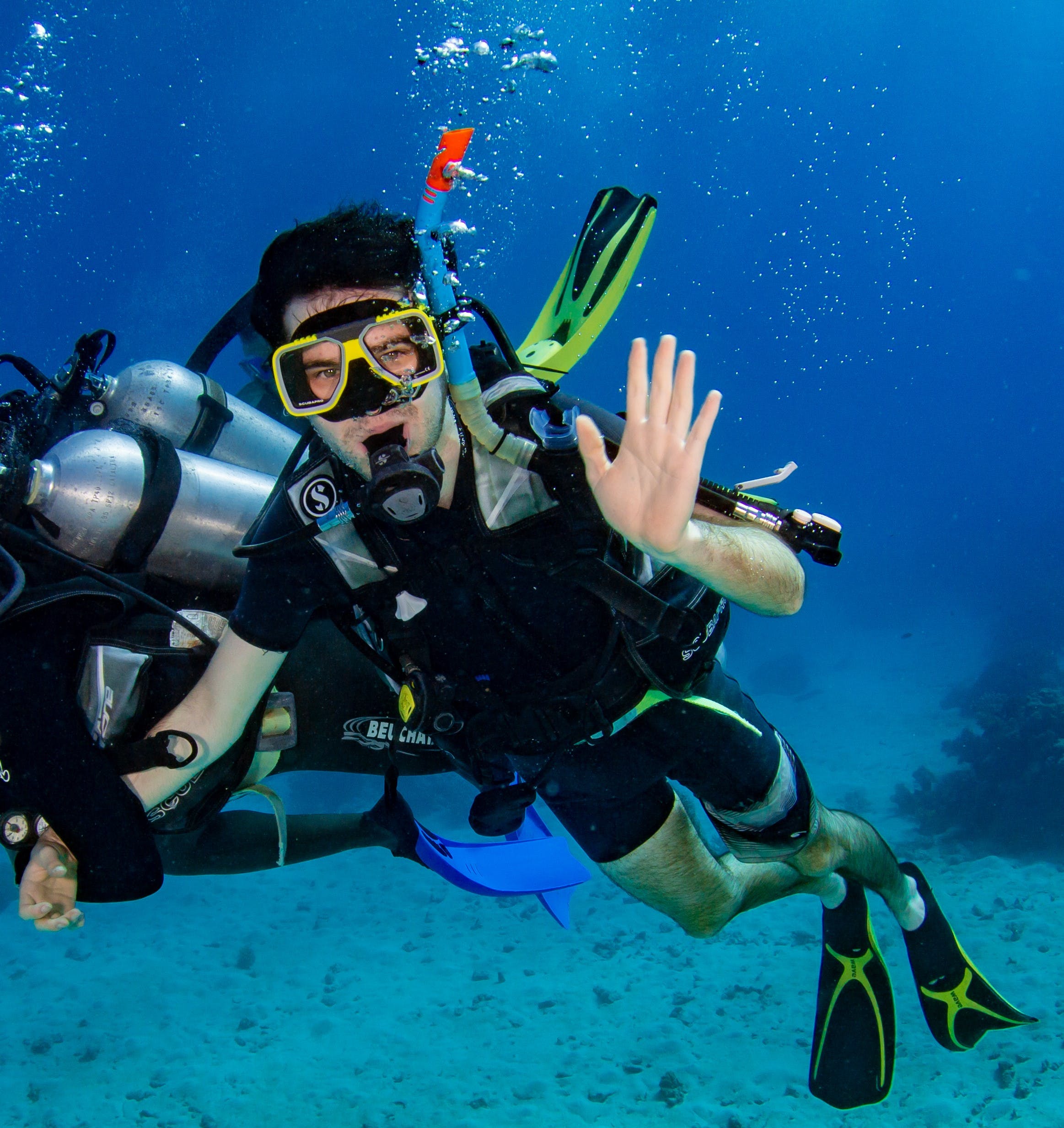 Alexander Hendry scuba diving and waving to the camera.