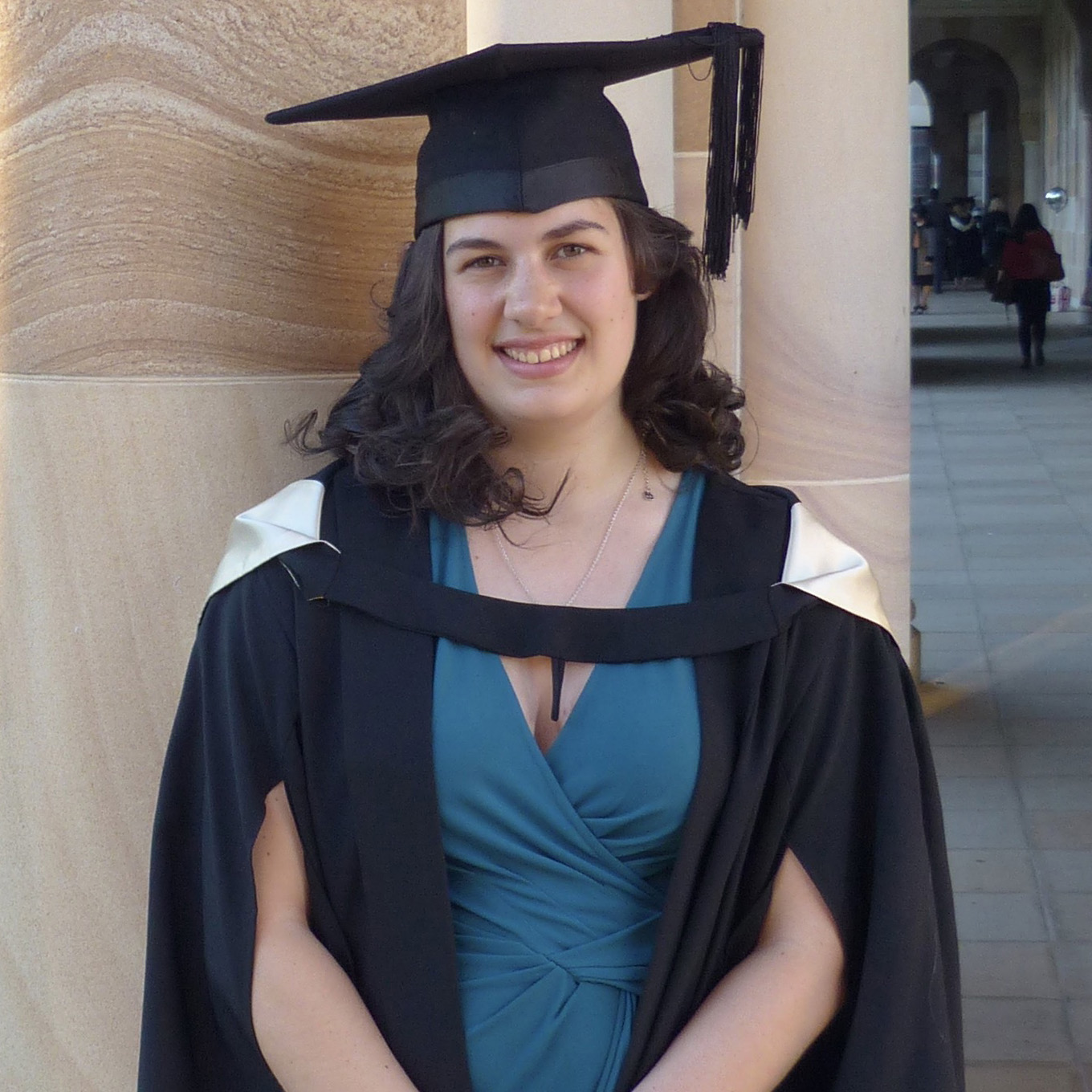 UQ graduate standing in front of Great Court sandstone