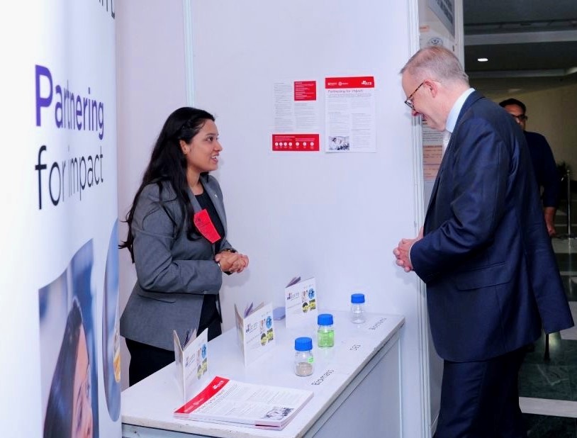 Vallari Chourasia talking to Australian Prime Minister, the Hon Anthony Albanese MP with pullup banner in foreground and lab samples on table