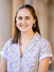 Arielle Blokker Arielle wears a floral blouse with hair down standing in front of sandstone pillars in the University of Queensland's Great Court