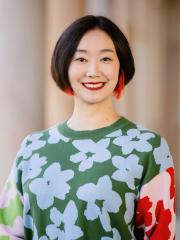 Lingyi Zhuge in the Great Court in front of sandstone columns wearing a floral multicoloured jumper