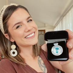 UQ student Adele Greedy-Vogel holding her NCP Scholar badge and smiling showing her teeth - very happy