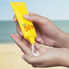 Sunscreen being poured onto hand of a woman