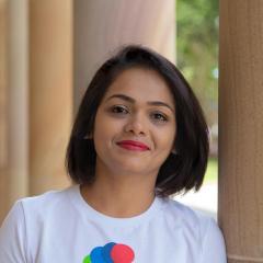 Runali wearing her t-shirt with circles shaped like a shell with the 17 sustainable development goals represented in differing colours. 