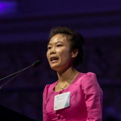 Douangmala speaking up on stage at the Australia Awards lecturn in a formal setting. 