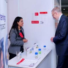 Vallari Chourasia talking to Australian Prime Minister, the Hon Anthony Albanese MP with pullup banner in foreground and lab samples on table