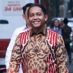 A smiling man (Raja Juli Antoni) wearing a brightly coloured shirt walks in the street in Indonesia.