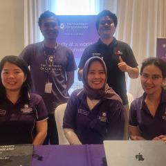 Miho Hamada with UQ colleages sitting at a table with UQ-Australia Awards alum standing behind. 