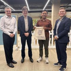Rian standing beside UQ academics with his bag with the UQ visualise your thesis log on it