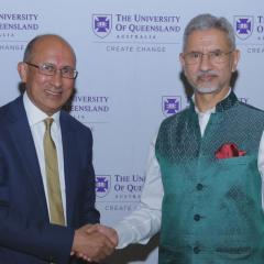 UQ Chancellor Peter Varghese AO shaking hand of Dr Subrahmanyam Jaishankar in front of University of Queensland media wall