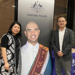 Miho Hamada stands with Khang Nguyen with an Australia Awards banner between them.