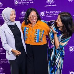 Three well-dressed women standing in front of purple Australia Awards and UQ media wall: Neludo Mgidiswa from Botswana, Chamon Ara Adoz from Bangladesh, and Veronica Peter Mafie from Tanzania.