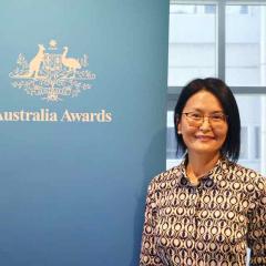 Professor Dr Enkhzaya Chuluunbaatar standing with an Australia Awards banner