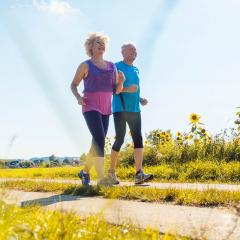 Two elderly people running through grass