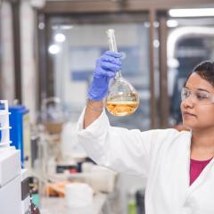 Indian phd candidate in chemistry lab looking at beaker