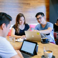 People sat at a table with laptops working together