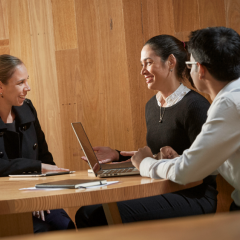 Three people sat at a table talking