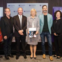 VC, panellists and Dallas Dowsett, Jessica Gallagher standing in front of a UQ media wall 