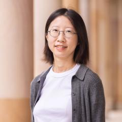 Lilly Zhao wearing glasses standing against Great Court sandstone pillars