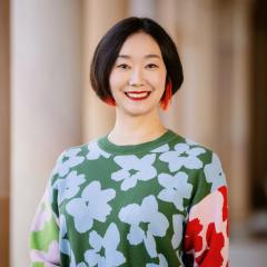 Lingyi Zhuge in the Great Court in front of sandstone columns wearing a floral multicoloured jumper