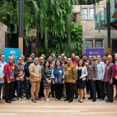 Participants standing for group photo in UQ's Global Change Institute atrium - which has a natural green wall behind them. 