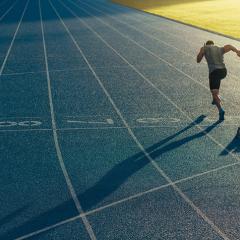 A Person running down a blue running track