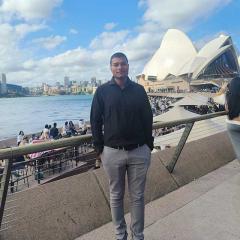 Harshal Verma standing at Sydney's Circular Quay with the Sydney Opera House behind him. 