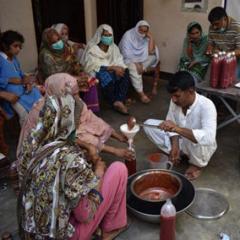 A group of people sit around a table in Bleberan village, Indonesia, to discuss a research plan with the farmers' group leader. 