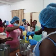 Women making yoghurt from milk in plain room - all women wearing hair nets and masks