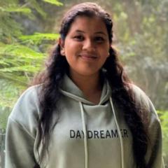 Shali Thevarasan wearing grey hoodie standing in front of greenery