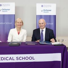 UQ VC Debbie Terry AO and CEO of Ochsner Health, Mr Pete November sittinga at table with banners in background at the signing