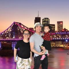 Miriam Agnes Yu and family standing in front of Brisbane skyline featuring the Story Bridge lit up in purple