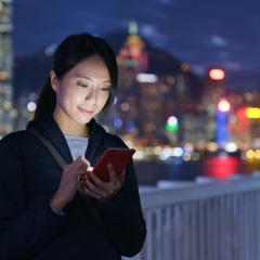 Woman looking at her phone by a river at night time