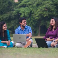 Students sitting the grass on laptops